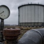 Ein großer Gasspeicherturm steht im Hintergrund, während ein Messgerät mit niedriger Anzeige und rostige Ventile im