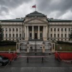 Das Verfassungsgericht in Warschau unter grauem Himmel, gesichert durch rote Absperrungen und einen Streifenwagen.